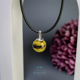 Perle als Kettenanhänger mit Tierhaaren und Blüten.