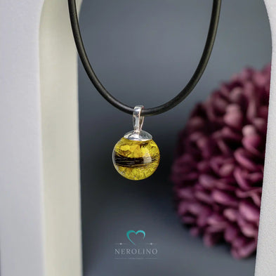 Perle als Kettenanhänger mit Tierhaaren und Blüten.