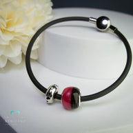 Perle halb mit Tierhaaren und Glitzerfarbe am Kautschukband. 